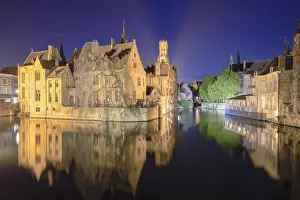 The medieval Belfry and historic buildings reflected in Rozenhoedkaai canal at night