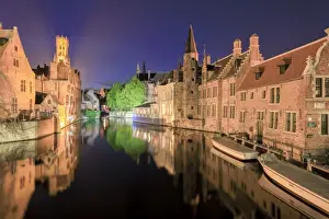 Bruges Prints: The medieval Belfry and historic buildings are reflected in Rozenhoedkaai canal at night