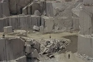 Quarry Prints: Men walking past clean faces for block extraction in granite quarry, Budduro