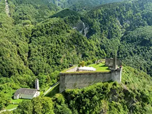 Attractions Prints: Mesocco castle sits atop a hill surrounded by trees in Tessino