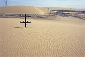 Western Desert Prints: Migrating barchan sand dunes across road marked by buried telegraph poles