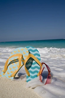 Images Dated 11th November 2007: Two mismatched beach flip-flops with red sunglasses in the surf on a Caribbean beach