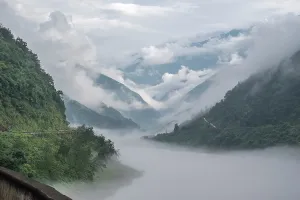 Peaks Prints: Misty mountain valley in Sichuan China with clouds covering slopes and a river flowing through the landscape