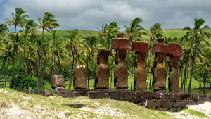 Landscaping Prints: Moai statues stand on the coast of Anakena with palm trees and hills in the background on Easter Island in Chile