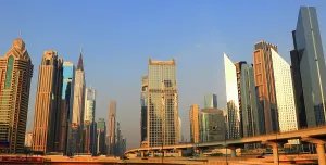 Skyscrapers Prints: Modern buildings rise high in central Dubai with clear blue skies above during daylight hours in the United Arab