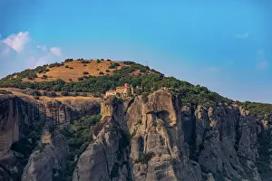Thessaly Prints: Monastery set on cliffs with green hill and blue sky in Meteora region of Greece