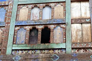 Bhutan Prints: Monk looking out of window with fading blue paint in Wangdue Chhoeling Palace, in