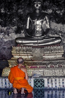 South East Asian Prints: A monk prays in front of a golden Buddha
