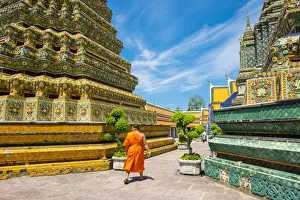A monk walks past stupas at Wat Pho (Temple of the Reclining Buddha), Bangkok, Thailand