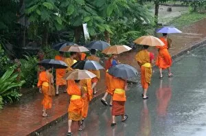 Monks in the rain in Luang Prabang, Luang Prabang, Laos, Indochina, Southeast Asia, Asia