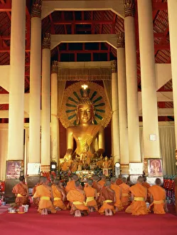 Buddha Prints: Monks in saffron robes kneel before a statue of
