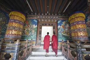 Images Dated 1st October 2009: Monks walking between prayer wheels at Trongsa Dzong (Chokhor Raptentse) dating from 1648