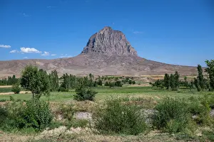 Rare Prints: Monolith stands tall along a road in Azerbaijan with clear blue sky and greenery in the foreground