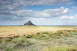 Retreat Prints: Mont Saint Michel rises from tidal flats under a cloudy sky in Normandy