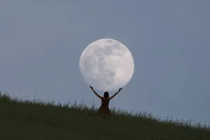 Full moon portrait at blue hour with a girl holding the moon above her head, Emilia Romagna, Italy, Europe Full moon portrait at blue hour with a girl holding the moon above her head, Emilia Romagna, Italy, Europe