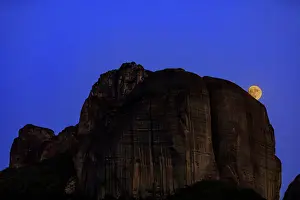 Wonders Prints: Full moon rises behind rock formations in Meteora, a UNESCO World Heritage site in Greece