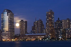 Full moon rising over Lower Manhattan skyline across the Hudson River