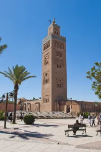 In Front Of Prints: Moroccan man sat on a bench in front of Koutoubia Mosque