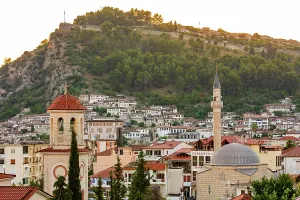 Albania Prints: Mosque and church stand above roofs of Berat with Kala Castle and Ottoman houses at sunset in Albania