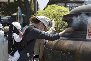 Images Dated 1st May 2009: Mother with baby using incense smoke to cure bodily ailments at Zenkoji Temple