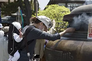 Nagano Prints: Mother with baby using incense smoke to cure bodily ailments at Zenkoji Temple