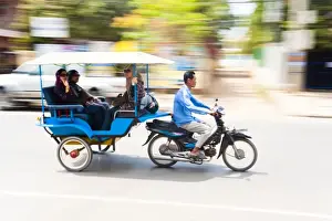 Pulling Prints: Motion blurred tourists in a tuk tuk speeding along the streets of Siem Reap
