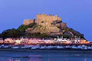 Mount Orgueil Castle, illuminated at dusk, overlooking Grouville Bay in Gorey