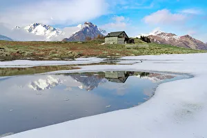 Valtellina Prints: Mountain hut on shore of frozen pond during thaw