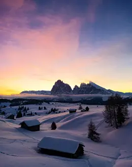 Mountain huts covered with snow at dawn with Sassopiatto and Sassolungo in background