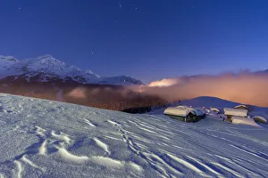 Mountain huts covered with snow under the starry winter sky, Andossi, Madesimo