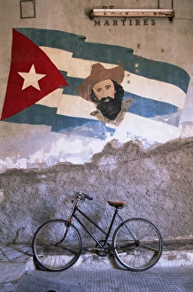 Cuban Prints: Mural of Camilo Cienfuergos on wall above a bicycle, Havana, Cuba, West Indies