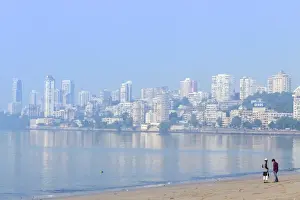 Mumbai Prints: A Muslim and a Hindu man talking on Chowpatty beach with the skyscrapers of wealthy Malabar Hill behind