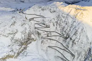 Snowcapped Prints: Narrow bends of the Stelvio Pass road on steep snowy mountain ridge, aerial view by drone