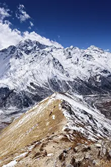 Challenge Prints: Narrow snow-covered ridge trail ascending toward Kyanjin Ri with panoramic views of Langtang Himal and Scout Peak
