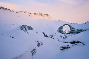 Northern Europe Prints: A naturally formed circular ice arch stands prominently amid the snow-covered landscape of Katla Glacier