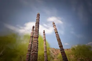 Poles Prints: Naxi poles with wood carvings with moving clouds in a long exposure
