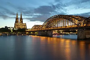 Floodlit Prints: Night view of Hohenzollern bridge and Cologne cathedral by the River Rhine in Cologne