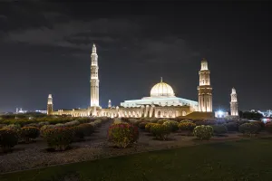Muscat Prints: Night view of Sultan Qaboos Mosque illuminated and the oleander field in the foreground