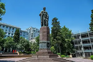 Daylight Prints: Nizami Ganjavi Monument stands tall in a city square under clear blue sky in Baku
