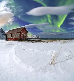 Northern Lights (aurora borealis) over an abandoned log cabin surrounded by snow