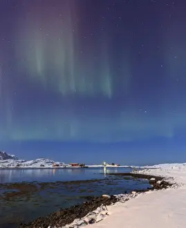 Northern lights (Aurora Borealis) on the snowy peaks reflected in the cold sea, Volanstinden