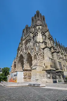 Spires Prints: Notre Dame cathedral in Reims shows detailed architecture and grand structure under clear sky in France