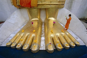 Large Prints: Novice monk praying at the feet of Giant Buddha statue
