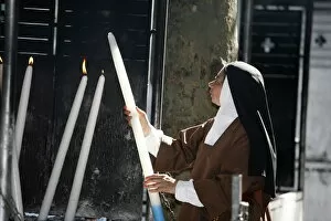 Images Dated 20th April 2000: Nun lighting a candle at the Lourdes shrine, Lourdes, Hautes Pyrenees, France, Europe