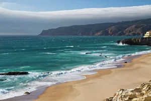 Ocean waves crashing on the sandy beach of Cascais, surrounded by cliffs, Estoril Coast