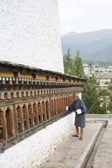 Old Bhutanese man turning prayer wheels in Buddhist temple, Thimphu, Bhutan, Asia