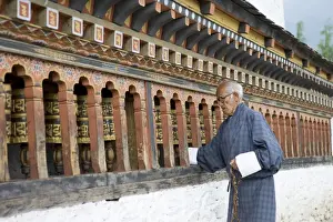 Prayer Wheel Prints: Old Bhutanese man turning prayer wheels in Buddhist temple, Thimphu, Bhutan, Asia