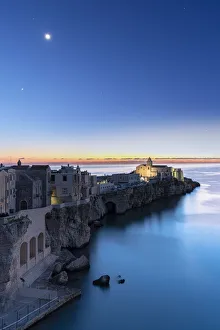 Apulia Prints: Old buildings and church of Vieste lit by moon at dusk, Vieste, Foggia province