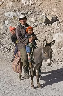 Old Kyrgyz man riding with twins on a donkey, Gulcha, Kyrgyzstan, Central Asia, Asia