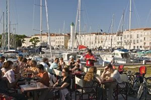 Open-air restaurant seating next to the ancient harbour at La Rochelle